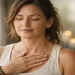 Woman pausing with hand on chest, listening to her body and inner signals after years of stress and disconnection