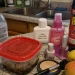 Kitchen countertop covered with plastic food containers, bottled water, personal care products, fast food packaging, and cookware representing everyday endocrine disruptors in daily life