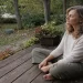 Woman sitting calmly on a wooden deck practicing stillness to support nervous system healing