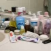 Cluttered bathroom countertop filled with everyday personal care products, bottles, and toiletries under flat natural lighting, showing ordinary household chemical exposure.