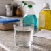 Glass of tap water on a kitchen counter with common household products nearby, representing everyday chemical exposure and misleading safety limits