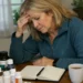 Woman sitting at table overwhelmed by multiple health supplements and notes
