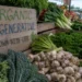 Farmers market display with vegetables and a wooden sign showing organic and regenerative farming practices.