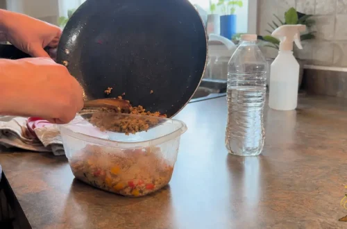 Everyday kitchen scene showing warm food placed in plastic beside a water bottle and household spray, representing endocrine disruptor exposure.