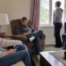 Four adults sitting together in a living room while looking at phones or away from one another, representing feeling disconnected.