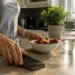 Woman turning her phone face-down while choosing fresh fruit and water in her kitchen